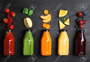 Flat lay composition with bottles of delicious juices and fresh ingredients on black table